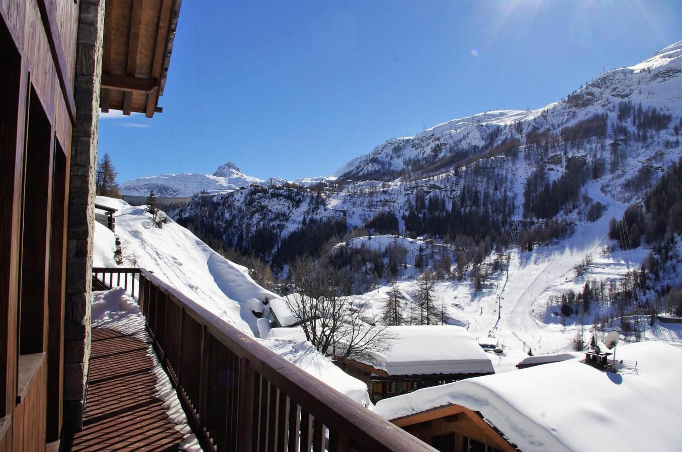 A wooden balcony with a view of a snow-covered mountain landscape.