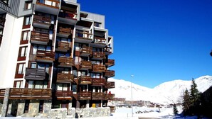 Ein mehrstöckiges Hotel mit Balkonen, einem Steinfundament und einer Bergkulisse.