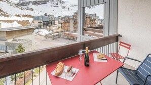 Ein Balkon mit einem roten Tisch, einer Weinflasche, einem Brot und einem Gebäckstück.