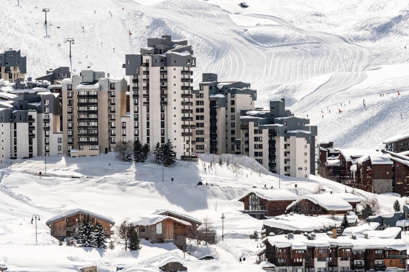 A snow-covered mountain resort with modern buildings and ski slopes.