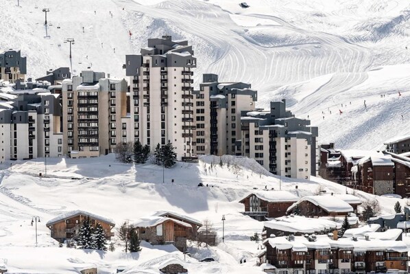 A snow-covered mountain resort with modern buildings and ski slopes.
