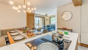 Una cocina moderna con una isla central, una mesa de comedor dispuesta para una comida y una zona de estar acogedora con sofá y una mesa de centro.