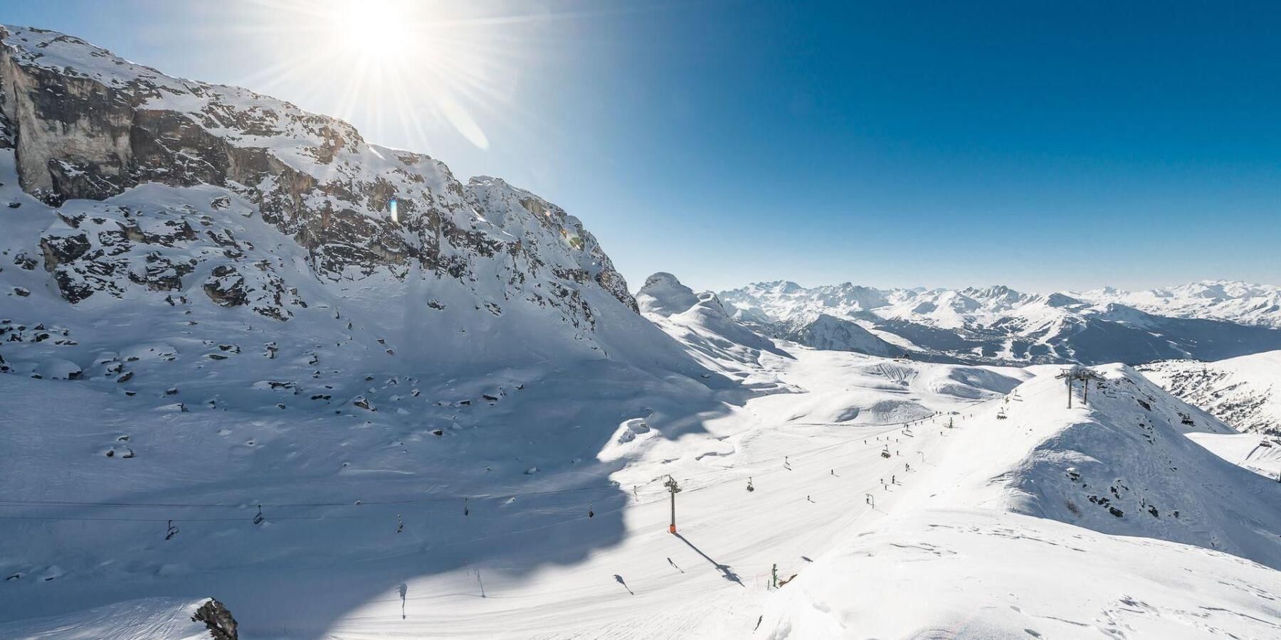 A snow-covered mountain landscape with ski slopes and a clear sky.