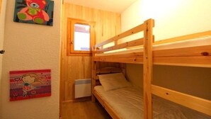 A small, cozy room with a bunk bed, a window, and a heater. - 250m from ski slopes, Ground floor, terrace, balcony, tv, ski locker, 65m², Champagny-en-Vanoise (Champagny-en-Vanoise)