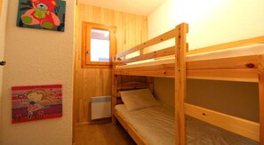 Ein kleiner, gemütlicher Raum mit einem Etagenbett, einem Fenster und einer Heizung.