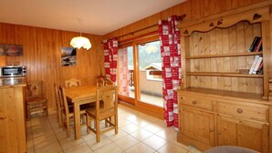A wooden interior with a dining table, chairs, a built-in bookshelf, and a window with red curtains. - 250m from ski slopes, Ground floor, terrace, balcony, tv, ski locker, 65m², Champagny-en-Vanoise (Champagny-en-Vanoise)