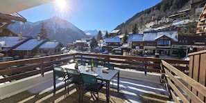 A terrace with a table and chairs, overlooking a snowy mountain town with buildings and a cinema. - 50m from ski slopes, 1st floor, terrace, tv, 35m², Champagny-en-Vanoise (Champagny-en-Vanoise)