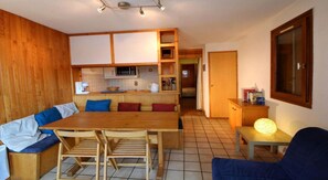 A compact living space with a wooden dining table, benches, a kitchenette, and a seating area with cushions. - 50m from ski slopes, 1st floor, terrace, tv, 35m², Champagny-en-Vanoise (Champagny-en-Vanoise)