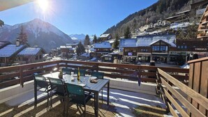 A terrace with a table and chairs, overlooking a snowy mountain town with buildings and a cinema. - 50m from ski slopes, 1st floor, terrace, tv, 35m², Champagny-en-Vanoise (Champagny-en-Vanoise)