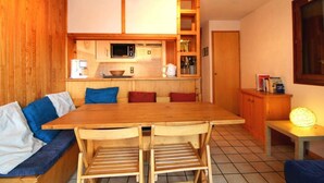 A compact kitchen with wooden cabinets, a microwave, and a small countertop. There is a dining table with chairs and a bench with cushions. - 50m from ski slopes, 1st floor, terrace, tv, 35m², Champagny-en-Vanoise (Champagny-en-Vanoise)
