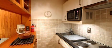 A compact kitchen with a microwave, stove, and sink.