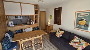 A compact living space with a kitchenette, a dining area, and a sofa with patterned cushions. - 50m from ski slopes, 1st floor, terrace, tv, 35m², Champagny-en-Vanoise (Champagny-en-Vanoise)