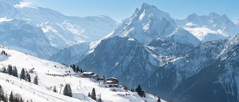 A snow-covered mountain landscape with a ski resort and buildings nestled among the peaks.