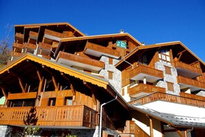 A multi-story wooden chalet with balconies, a stone facade, and a sign indicating it is a ski resort. - 200m from ski slopes, 4th floor, balcony, tv, ski locker, 65m², Champagny-en-Vanoise (Champagny-en-Vanoise)