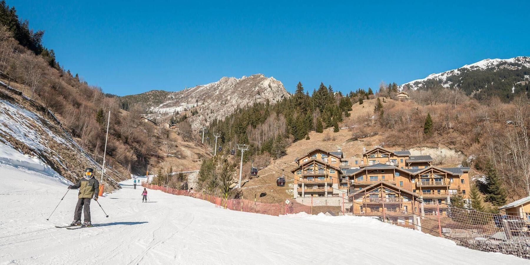 A ski resort with wooden lodges, a ski lift, and a snow-covered slope.