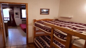 A room with a bunk bed, a red sofa, a small table, and a framed picture on the wall. - 50m from ski slopes, 2nd floor, balcony, tv, 21m², Champagny-en-Vanoise (Champagny-en-Vanoise)