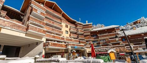 Un hôtel à plusieurs étages doté de balcons, d’une enseigne indiquant un service de location de matériel de ski et d’un restaurant.