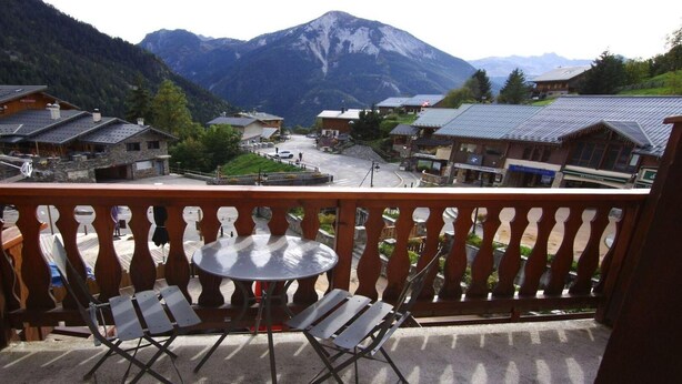 A balcony with a table and chairs overlooking a mountain village with traditional buildings. - 50m from ski slopes, 2nd floor, balcony, tv, 21m², Champagny-en-Vanoise (Champagny-en-Vanoise)
