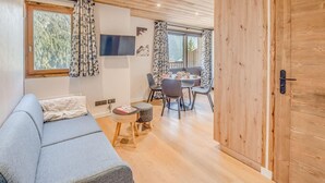A modern living room with a sofa, a small table, and a dining area with chairs and a table. - Resort center, 4th floor, balcony, tv, 29m², Champagny-en-Vanoise (Champagny-en-Vanoise)