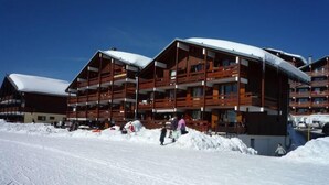 A multi-story wooden building with balconies, surrounded by snow. - 100m from ski slopes, 1st floor, view ski slopes, balcony, tv, ski locker, 28m², Les Saisies (Les Saisies)