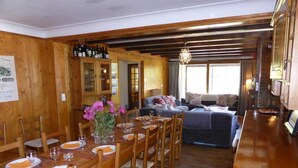 Un interior de madera con comedor para seis personas, un sofá y una zona de bar.