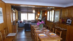 Un comedor de madera con una larga mesa dispuesta para seis personas, flanqueada por sillas de madera.