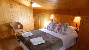 Un dormitorio con paneles de madera, una cama, dos lámparas de noche, una silla y una puerta.