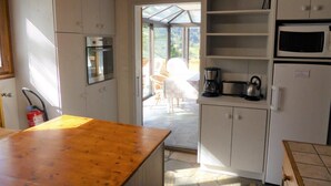 Una cocina con armarios blancos, encimera de madera, microondas y cafetera.