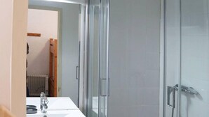 A modern bathroom with a glass-enclosed shower, a white sink, and a mirror above the sink.