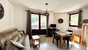 A cozy living room with a sofa, a dining table, and a TV.