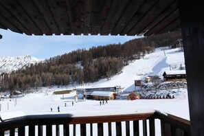 A snowy mountain landscape with a ski resort, including a wooden building and a ski lift.