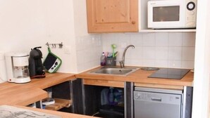 A kitchen with wooden cabinets, a microwave, a coffee maker, and a dishwasher. - 10m from resort center, 1st floor, view ski slopes, terrace, tv, ski locker, 30m², Montgenèvre (Montgenèvre)