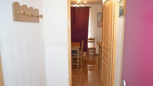 A hallway with a wooden door, a dining area with a table and chairs, and a wall-mounted wooden decoration. - 10m from resort center, 1st floor, view ski slopes, terrace, tv, ski locker, 30m², Montgenèvre (Montgenèvre)