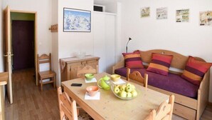 A cozy room with a wooden table set with bowls and apples, a wooden sofa with colorful cushions, and a painting on the wall. - 10m from resort center, 1st floor, view ski slopes, terrace, tv, ski locker, 30m², Montgenèvre (Montgenèvre)