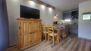 Une cuisine de taille réduite, dotée de meubles en bois, d’une table à manger et de chaises.