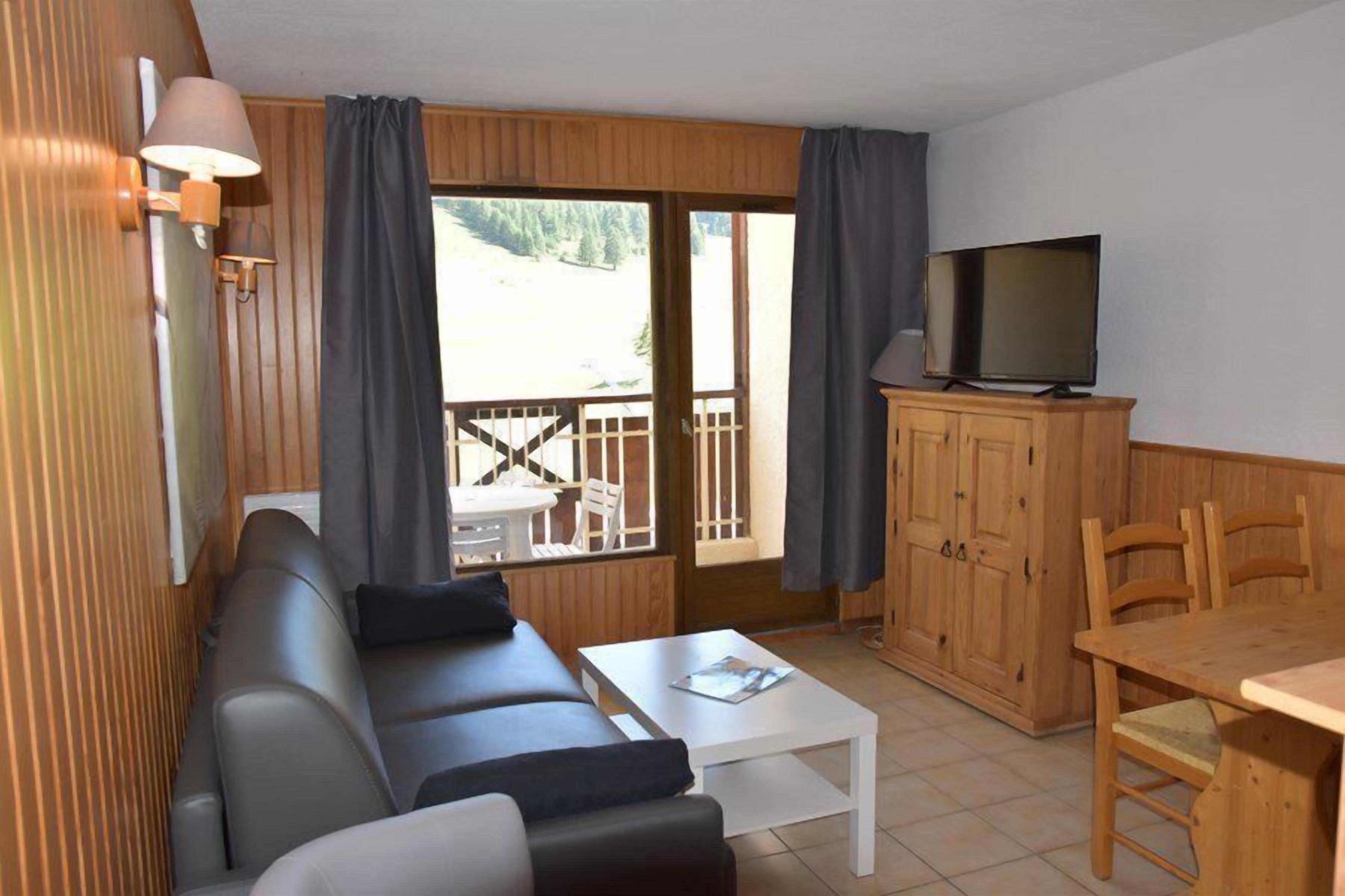 Una sala de estar acogedora con un sofá, una mesa de centro, un televisor y armarios de madera.