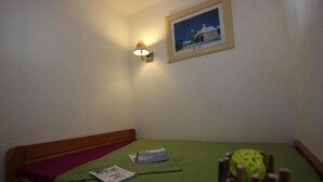 A small, simple room with a single bed, a wall-mounted light, and a framed picture. - 100m from ski slopes, 2nd floor, balcony, tv, 24m², Val Thorens (Val Thorens)