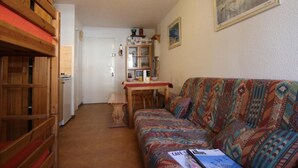 A cozy living room with a patterned sofa, wooden furniture, and a dining area with a table and chairs. - 100m from ski slopes, 2nd floor, balcony, tv, 24m², Val Thorens (Val Thorens)