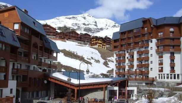 A hotel with multiple floors, a ski slope in the background, and a parking area with cars. - 100m from ski slopes, 2nd floor, balcony, tv, 24m², Val Thorens (Val Thorens)
