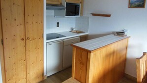 Eine kleine Küche mit Holzausstattung, einer Mikrowelle, einem Geschirrspüler und einer Arbeitsinsel.