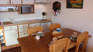 A compact kitchen with white cabinets, a microwave, and a dining table with chairs.