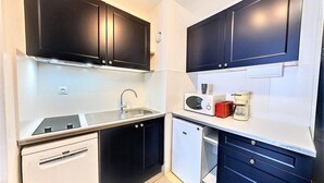 A compact kitchen with dark cabinets, a sink, a microwave, a coffee maker, and a small refrigerator. - 10m from ski slopes, 10th floor, view ski slopes, swimming pool, balcony, tv, ski locker, 22m² (Le Corbier)