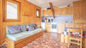 Eine kompakte Küche mit Holzausbau, einem eingebauten Backofen und einem Essbereich mit Tisch und Stühlen.