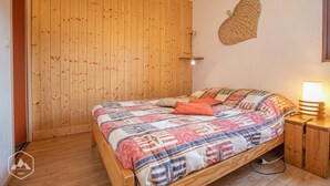 Ein Zimmer mit Holzwandverkleidung, einem Bett, einer Wandlampe und einer gewebten Wanddekoration.