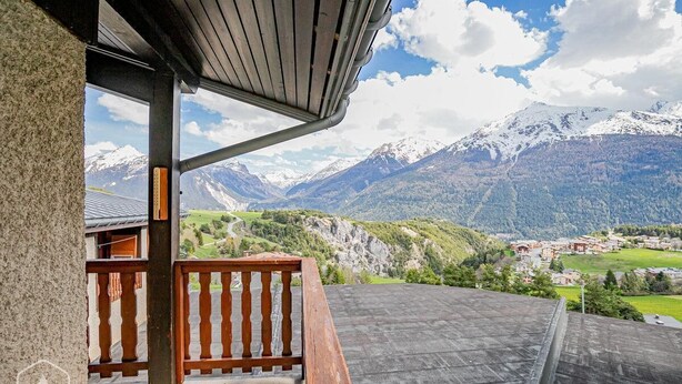 Ein Balkon mit Blick auf schneebedeckte Berge und ein Dorf darunter.