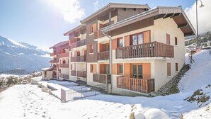Un hôtel à plusieurs étages, doté de balcons, situé dans une région montagneuse enneigée.