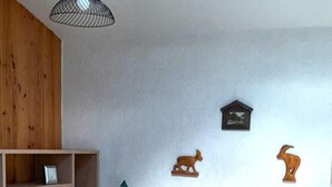 Une chambre à coucher avec un lit en bois, un luminaire suspendu, une tête de lit en bois et une petite étagère sur laquelle est posé un cadre photo.