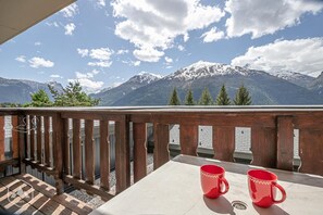 A balcony with a view of snow-capped mountains, two red mugs on a table, and a wooden railing. - 150m from ski slopes, floor -1, balcony, tv, ski locker, 21m², Aussois (Aussois)