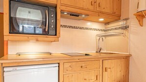 A compact kitchen with wooden cabinets, a built-in microwave, a sink, and a small refrigerator. - 150m from resort center, 2nd floor, balcony, tv, ski locker, 29m², Aussois (Aussois)