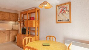 A cozy room with a wooden dining table, chairs, a lofted wooden staircase, and a framed poster on the wall. - 150m from resort center, 2nd floor, balcony, tv, ski locker, 29m², Aussois (Aussois)